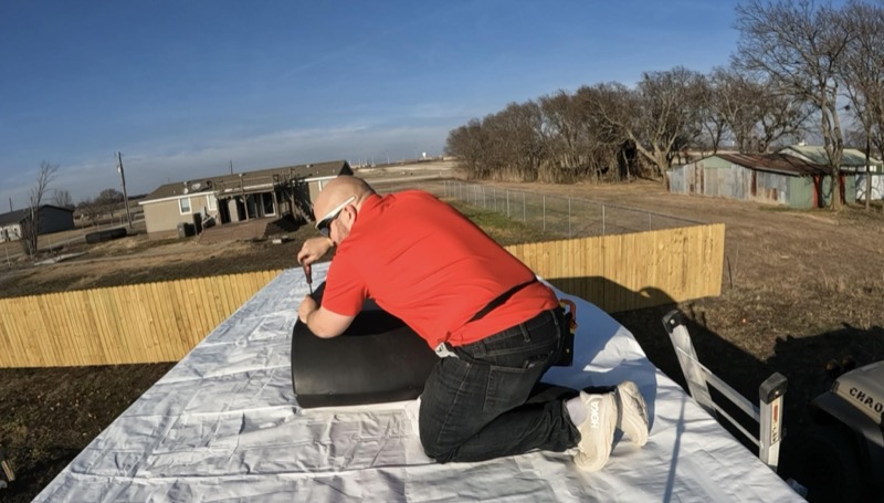Nick on top of an RV performing roof repair and seal work
